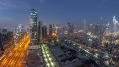 Dubai 'nin iş sahası kulelerinin panoraması gece gündüz geçiş zamanı. Güneş doğmadan önce inşa halindeki bazı gökdelenlerin ve yeni binaların çatı manzarası