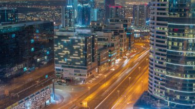 Dubai 'nin iş hanı binaları gece hava trafiğiyle dolu. Bazı gökdelenlerin çatı manzarası ve inşaat halindeki yeni kuleler