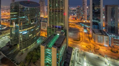 Dubai Uluslararası Finans Merkezi gökdelenleri gece gündüz geçiş zamanları. Güneş doğmadan önce yukarıdan parkedilmiş panoramik manzaralı kuleler