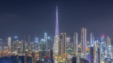 Dubai şehir merkezinin panoramik silueti ve Business Bay semtinin gece zaman çizelgesi. Birçok modern gökdelenin havadan görünüşü. Birleşik Arap Emirlikleri.