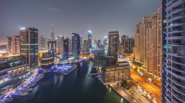 Dubai marinasının hava panoramik görüntüsü kanalın etrafındaki gökdelenleri gece gündüz yüzen yatlarla aydınlattı. Güneş doğmadan önce beyaz tekneler yat kulübüne park edilir.
