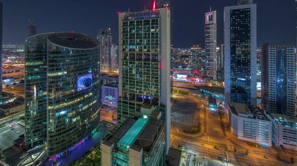迪拜国际金融中心的摩天大楼从空中飞驰而过 照明塔和停车场全天候亮着灯 — 图库照片