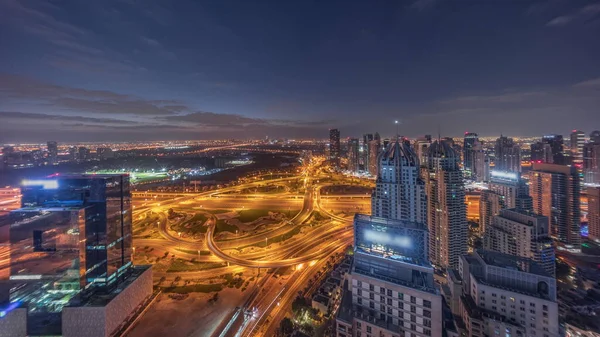 Jlt区与迪拜码头之间的巨大公路交叉口 通过谢赫扎耶德路的空中昼夜过渡全景时间 在交通繁忙的照明塔和摩天大楼附近的高尔夫球场 — 图库照片