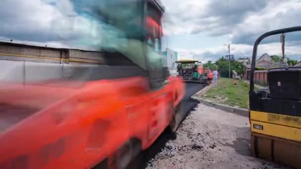 Un terminador de pavimentadora, un terminador de asfalto o una máquina de pavimentación colocando una capa de asfalto durante un proyecto de construcción de pavimentación timelapse — Vídeo de stock