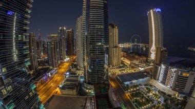 Dubai Marina ve JBR bölgesinin panoraması ve ünlü Ferris Wheel gece gündüz geçiş zamanı. Gün doğumunda uzun gölgelerle aydınlatılmış gökdelenler