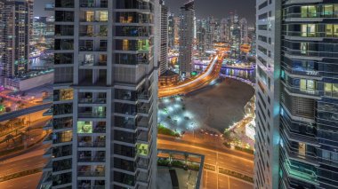 Dubai Marina ve JBR bölgesini gösteren panorama ve ünlü Ferris Wheel hava gece zaman çizelgesi ve aydınlatılmış gökdelenler ve caddelerde trafik