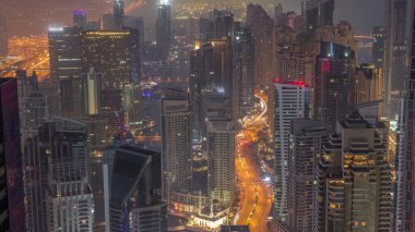 Dubai Marina 'nın Vew' ı, kıyı şeridi boyunca aydınlık gökdelenlerle çevrili kanalı gösteriyor. Gece gündüz geçiş zamanı. Güneş doğmadan önce yüzen yatlar ve tekneler. Dubai, BAE