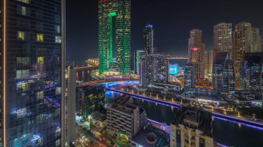 Panorama, Dubai Marina gökdelenlerini ve JBR bölgesini lüks binalar ve dinlenme yerleri ile gösteriyor. Aydınlatılmış rıhtım ve kanalda yüzen tekneler