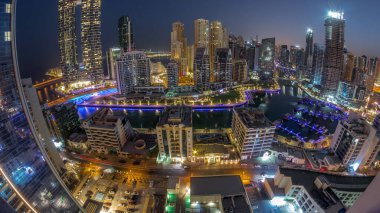 Dubai Marina Panoraması 'nda limana park edilmiş tekne ve yatlar ve gün doğumundan önce gece gündüz kanal havası çevresindeki gökdelenleri aydınlatıyordu. Arka planda JBR bölgesi kuleleri