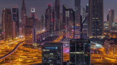 Dubai Finansal Merkezi 'nin panoraması. Gece gündüz aydınlatma saatleri olan yüksek gökdelenleri var. Gün doğmadan önce yoğun karayolu boyunca kulelerin hava görüntüsü