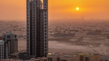 Barsha Heights semtindeki gökdelenler üzerinde gün doğumu ve arka plandaki hava zaman aralıklı villalar. Dubai silueti turuncu gökyüzü ile sabah