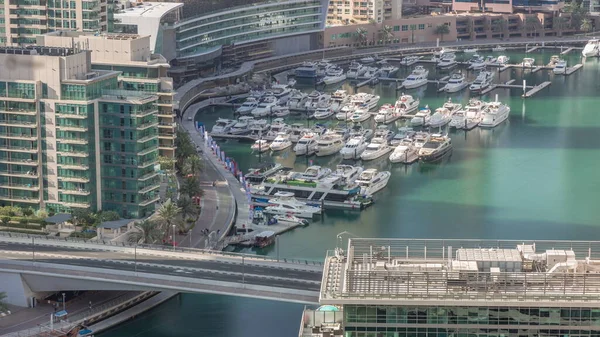 Kanal çevresindeki Dubai marina gökdelenlerine doğru yüzen botların zaman ayarlı görüntüsü. Beyaz tekneler yat kulübüne park edilmiş. Sabah hareket eden gölgelerle dolu bir köprüde trafik vardı.