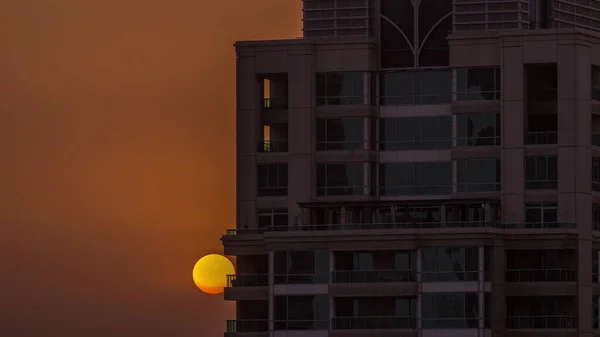 超高層ビルの空中タイムラプスの後ろに太陽が昇るドバイマリーナ高級観光地の日の出 住宅やオレンジの空 — ストック写真