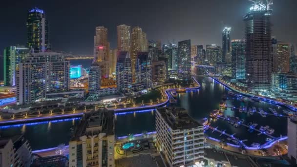 Dubai Marina with several boat and yachts parked in harbor and skyscrapers around canal aerial night timelapse. — Stock Video