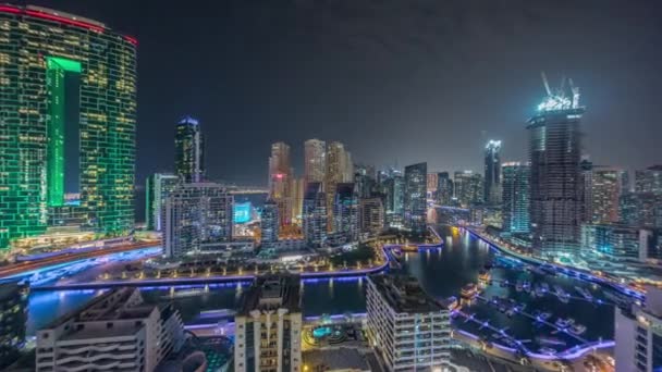 Dubai Marina con varios barcos y yates estacionados en el puerto y rascacielos alrededor del canal de la noche aérea timelapse. — Vídeo de stock