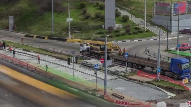 Кран-погрузчик для погрузки и разгрузки трамвайных рельсов с грузовика, который стоит на строительной площадке — стоковое видео