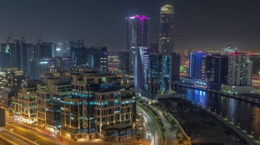 Körfez Meydanı Bölgesi gece zaman dilimi. Karışık kullanım ve Dubai 'deki Business Bay' de bulunan düşük katlı kompleks ofis binaları. Yukarıdan hava manzaralı ve yolda trafik var.