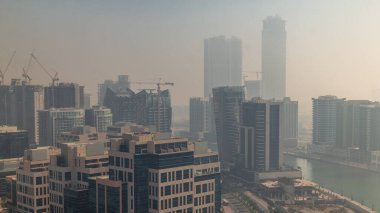 Gündoğumunda Business Bay bölgesinde modern şehir mimarisi. Dubai 'nin gökdelenlerinin panoramik hava görüntüsü trafik varken zaman ayarlı. Gün doğumunda sisli hava
