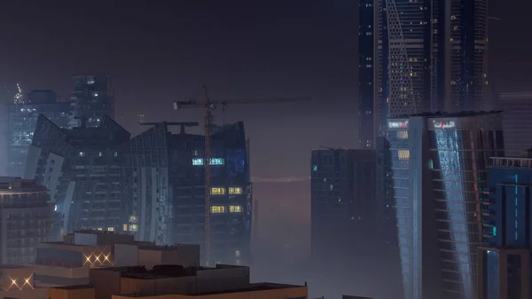 ビルビジネスベイの夜のタイムラプスで霧の厚い層で覆われている ライトアップされた高層ビルや工事現場の空中展望 — ストック写真