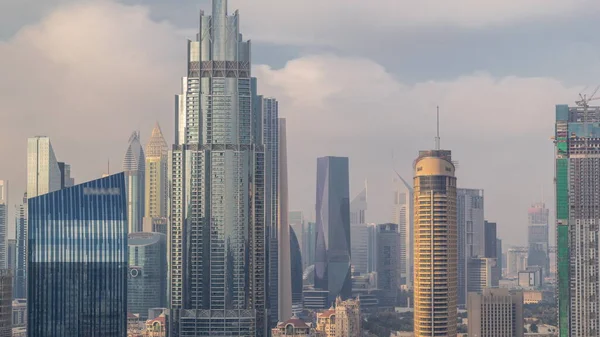 Dubai şehir merkezinden yükselen gökdelenler, alışveriş merkezi ve finans merkezi modern binalarla çevrili. Gökyüzü bulutlu.