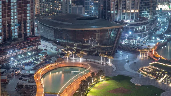 Şehir merkezinde yer alan Dubai Operası, Dubai 'de gece saatlerinde ışıl ışıl bir kültür ve sanat merkezidir. Aydınlatılmış yapay göl ve park, yukarıdan palmiye manzaralı.