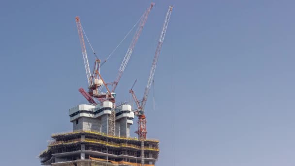 Edificio alto en construcción. El sitio con grúas contra el cielo azul — Vídeo de stock