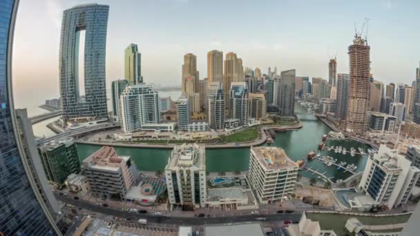 Panoramisch uitzicht op Dubai Marina met verschillende boten en jachten geparkeerd in de haven en wolkenkrabbers rond kanaal antenne dag tot nacht timelapse. — Stockvideo