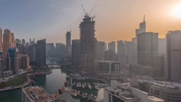 Dubai Marina with several boats and yachts parked in harbor and skyscrapers around canal aerial all day timelapse. — Stock Video