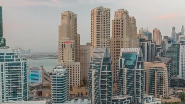 Dubai Marina z kilkoma łodziami i jachtami zaparkowanymi w porcie i drapaczami chmur wokół kanału lotniczego dzień do nocy. — Wideo stockowe