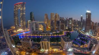 Dubai Marina Panoraması 'nda limana park etmiş çok sayıda tekne ve yat ve gökdelenler gece gündüz kanal antenleri etrafında.