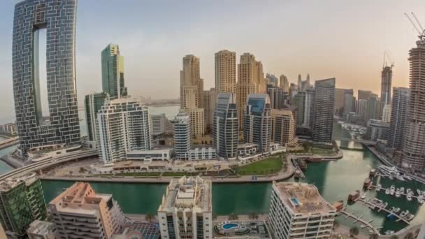 Dubai Marina with several boats and yachts parked in harbor and skyscrapers around canal aerial morning timelapse. — Stock Video