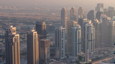 Şeyh Zayed Yolu yakınlarındaki JLT gökdelenleri. Arkasında konut binaları ve villalar var. Gün batımında sisli hava