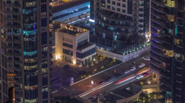 Gökdelenler ve büyük bir zaman diliminde park yeri arasındaki yol kesişiminin havadan görüntüsü. BAE 'nin Dubai Marina bölgesinin şehir manzarası. Arabaları ve pencereleri olan lüks kuleleri var.