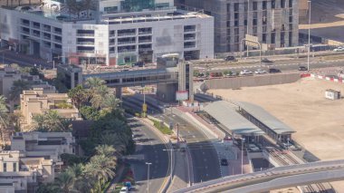 Dubai Marina 'daki tramvay istasyonunda, yaya köprüsü hava saatleri var. Kavşakta ve üstgeçitte trafik var. Yukarıdan görüntüle