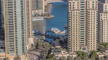 Yatı yüzen gökdelenler ve tekneler arasındaki kavşağın hava görüntüsü. BAE 'nin Dubai Marina bölgesinin şehir manzarası. Çeşmenin etrafında arabalar ve palmiyeler var.