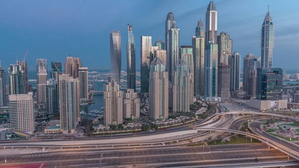 Dubai Marina karayolu kavşağı spagetti kavşağı gece gündüz geçiş zamanı. Arka planda en uzun gökdelenler aydınlatılıyor. Güneş doğmadan önce JLT bölgesinden hava üst görünümü