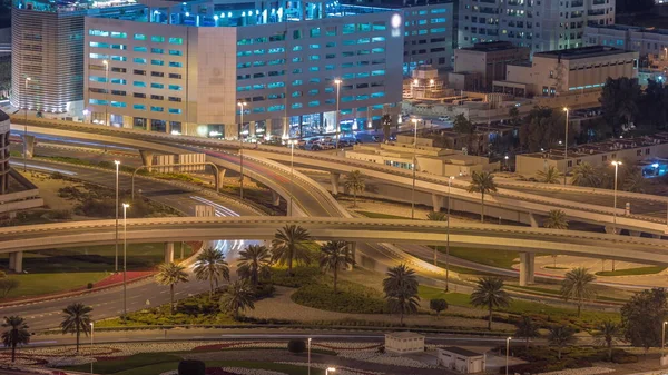 Dubai Marina 'da büyük bir karayolu kavşağında hava manzarası. Çok katlı bir park yeri ve BAE' nin etrafında gökdelenler var. JLT bölgesinden araba trafik görüntüsü. Çimenler ve palmiyeli ağaçlar