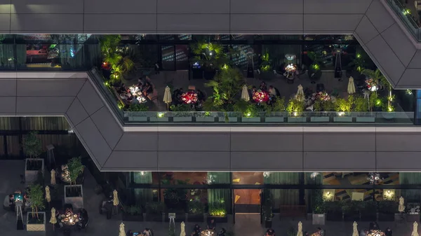 Açık havada, gece vakti açık havada rahat bir restoranın havadan görünüşü. İnsanlar Dubai 'nin finans bölgesinde masalarda oturuyor.