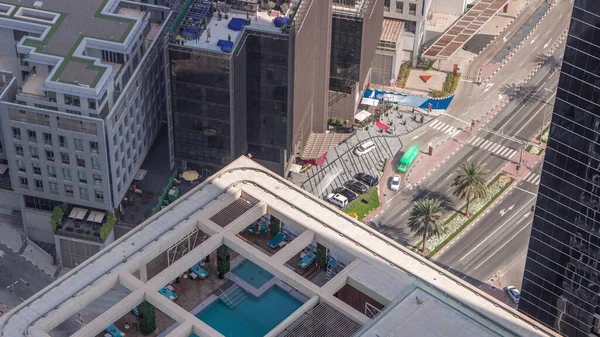 Çatıdaki yüzme havuzu yukarıdan izleniyor. Gölgeler hızlı hareket ediyor. Trafiği ve park yeri olan finans bölgesinin havadan görüntüsü. İnsanlar rahatlıyor. Dubai, BAE
