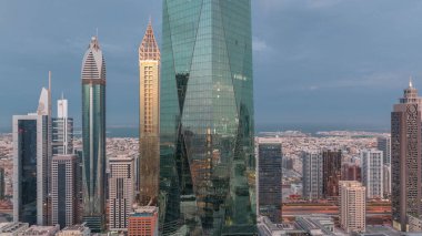 Dubai 'nin finans merkezi, gece gündüz aydınlık lüks gökdelenler geçiş zamanı, Dubai, Birleşik Arap Emirlikleri. Pencerelerde ve ofis kulelerinde ışık olan hava manzarası