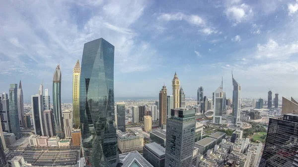 Sheikh Zayed karayolu zaman çizelgesinde Dubai 'deki finans bölgesi iş merkezindeki fütürist gökdelenlerin panoraması. Yukarıdan gökyüzü mavi bulutlu.