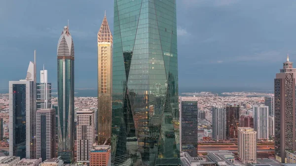 Dubai 'nin finans merkezi, gece gündüz aydınlık lüks gökdelenler geçiş zamanı, Dubai, Birleşik Arap Emirlikleri. Pencerelerde ve ofis kulelerinde ışık olan hava manzarası