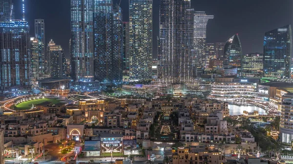 Gökdelenlerle çevrili eski kasaba adasının aydınlatılmış geleneksel evlerinin gökdelenlerle dolu gece manzarası. Dubai şehir merkezinde alışveriş merkezi ve çarşıya yakın çeşme alanı var.