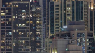 Modern konut binalarındaki büyük parlayan pencereler geceleri zaman ayarlı, sıra sıra parlıyor. Aydınlatılmış gökdelen