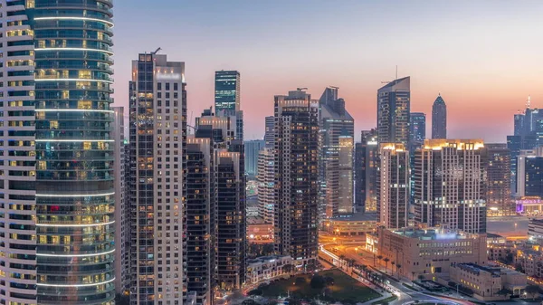 在迪拜 商业中心的塔楼从天到晚都在过渡 日落后一些摩天大楼和在建的新建筑物的屋顶视图 灯亮着 — 图库照片