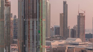 İnşaat halindeki çok katlı binalar ve birçok vinç zaman ayarlı. Asansörler ve işçiler ön cephede hareket ediyorlar. Gün batımında yeni kulelerin ve gökdelenlerin inşaatında aktif iş