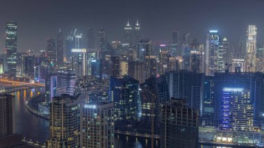 Dubai 'nin modern mimarisine sahip Skyline gece kuleleri aydınlatıyordu. Kanal ve inşaat alanında tekneleri olan hava manzarası