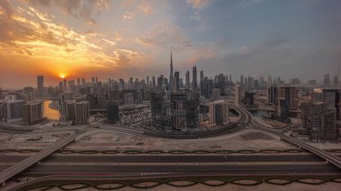 Dubai 'nin panoramik ufuk çizgisi üzerinde gün batımı iş sahası ve şehir merkezi zaman çizelgesi. Renkli bulutları ve ışık ışınları olan birçok modern gökdelenin havadan görünüşü. Birleşik Arap Emirlikleri.