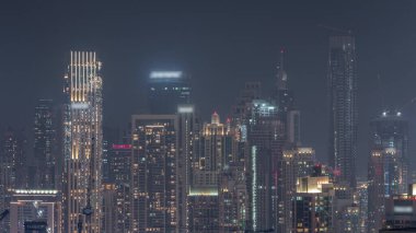 Dubai 'nin panoramik silueti. İş sahası ve şehir merkezi gece zaman çizelgesi yukarıdan. Birçok modern gökdelenin havadan görünüşü. Birleşik Arap Emirlikleri.
