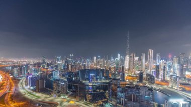 Dubai 'nin panoramik silueti. İş sahası ve şehir merkezi gece zaman çizelgesi yukarıdan. Birçok modern gökdelenin havadan görünüşü. Birleşik Arap Emirlikleri.